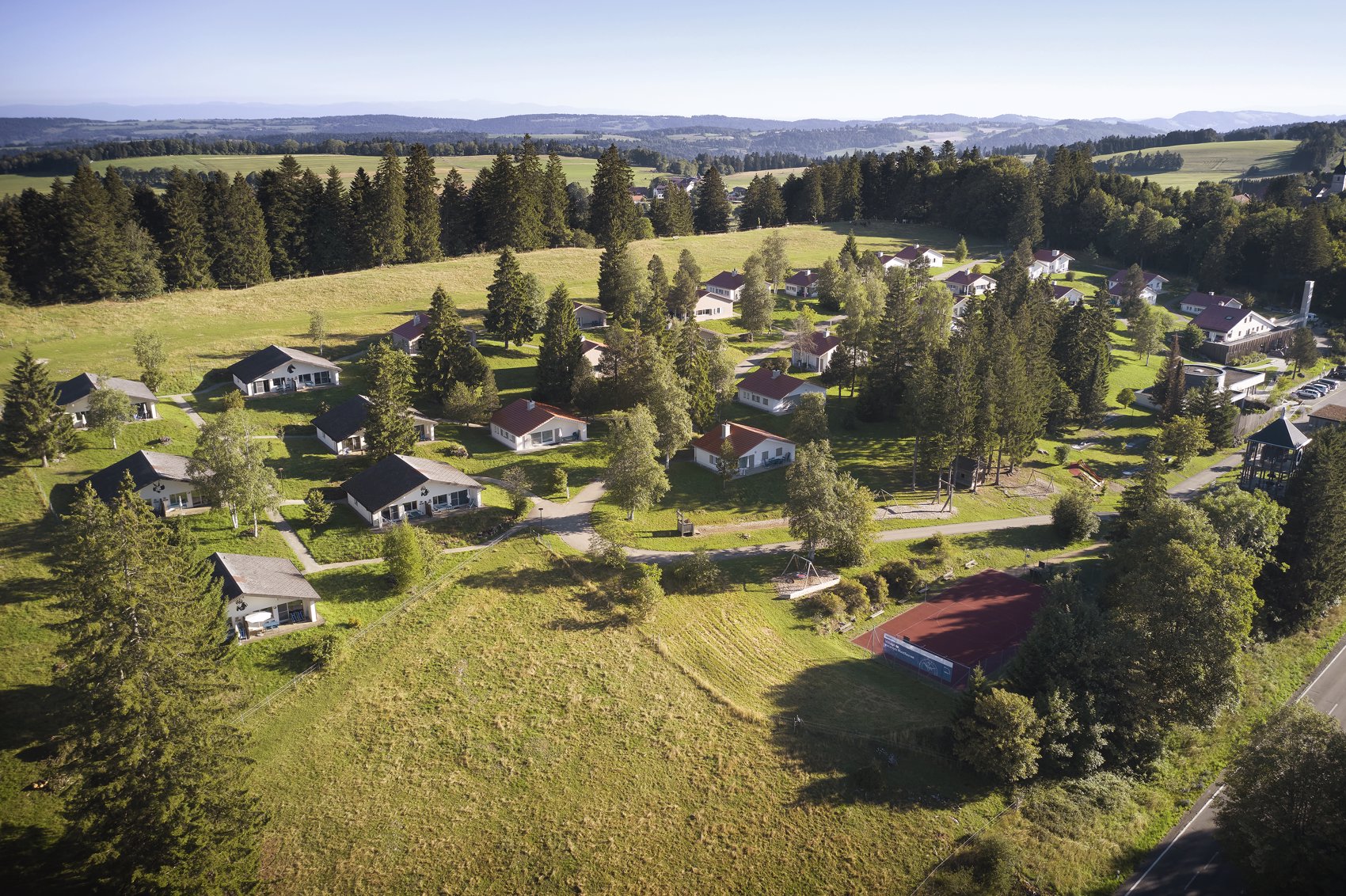 Exterior view in summer - Reka Holiday Village Montfaucon reka-holiday-village, montfaucon, western-switzerland Exterior view in summer - Reka Holiday Village Montfaucon reka-holiday-village, montfaucon, western-switzerland